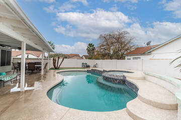 Kidney shaped pool surrounded by light colored stamped concrete pool deck in Frisco, Texas