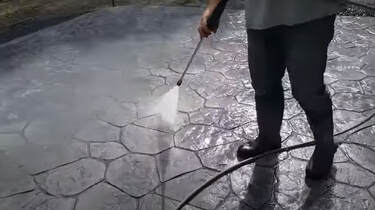 Man spraying protective sealant on a stamped concrete deck in Frisco, Texas
